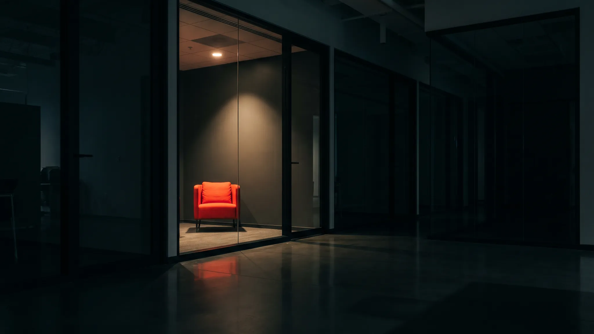 Un corridoio di uffici di notte, una sola sala accesa con una poltrona rossa